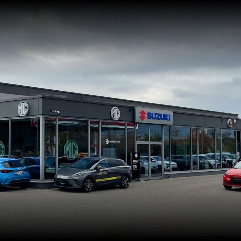 Autohandel mit moderner Fassade, mehreren Autos vor dem Gebäude.