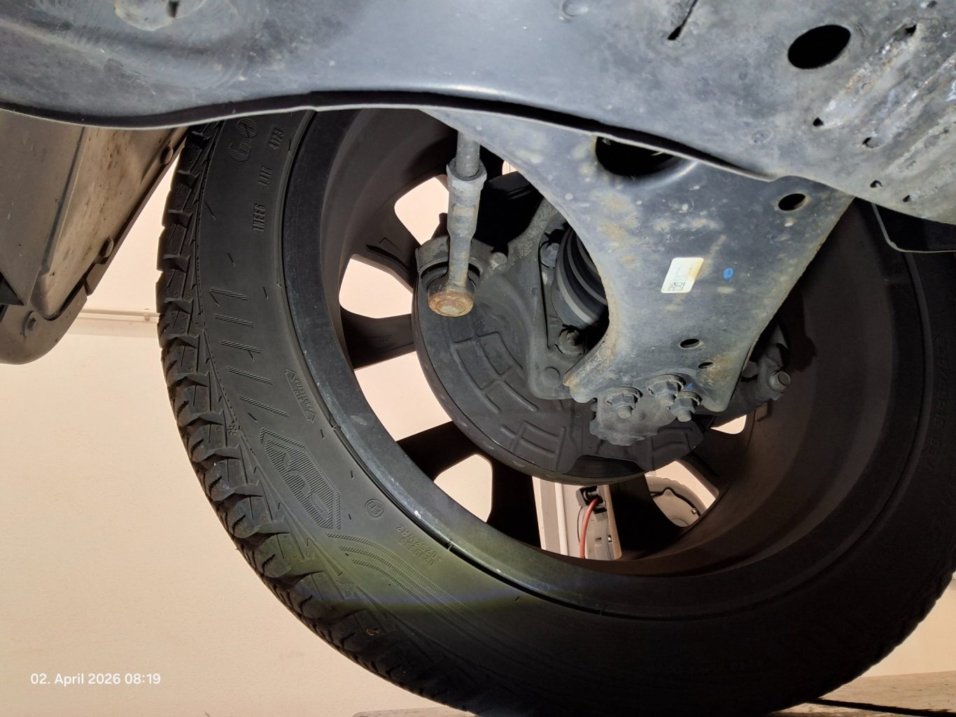 Detailansicht eines autotypischen Rades mit Reifen und Aufhängungsteilen.